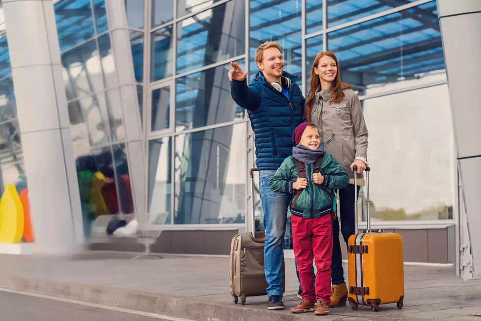 flughafentransfer junge Familie mit Koffern wartet am Flughafen auf den Transfer
