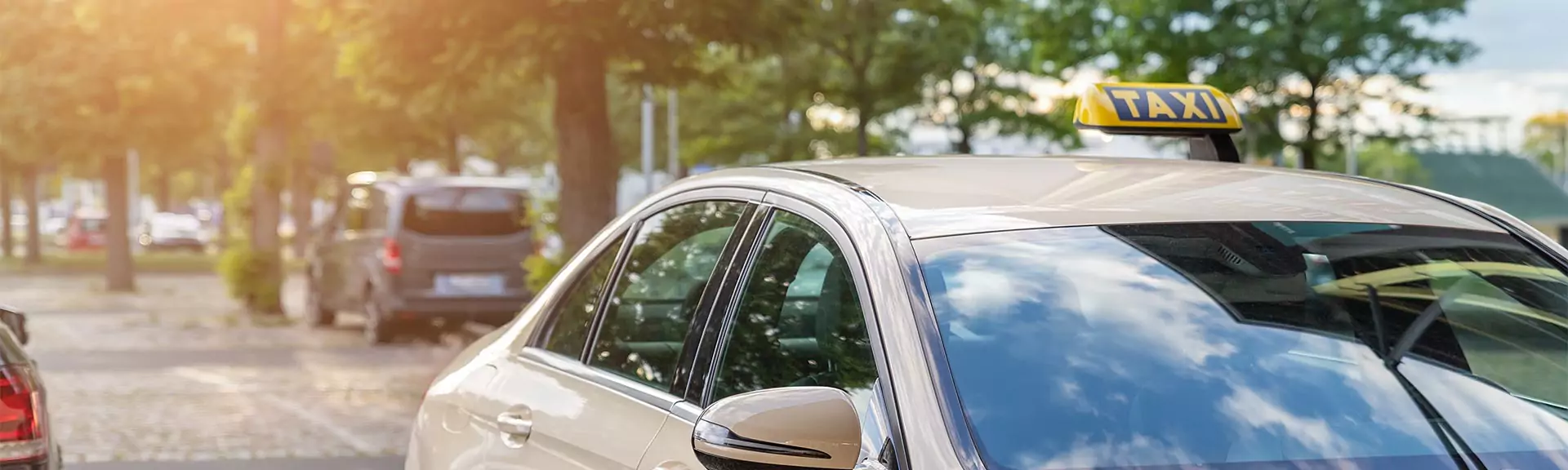 taxi strasse Nahaufnahme eines fahrenden Taxis mit anderen Autos und Bäumen im Hintergrund